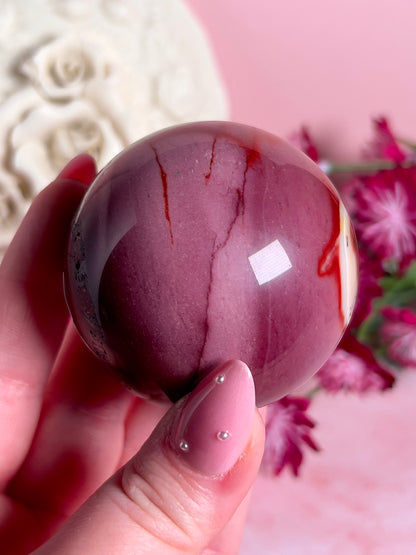 hand holding mookaite sphere